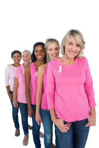 Group of women wearing pink tops and ribbons for breast cance on white background