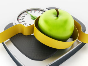 Green apple and tape measure on weight scale isolated on white background