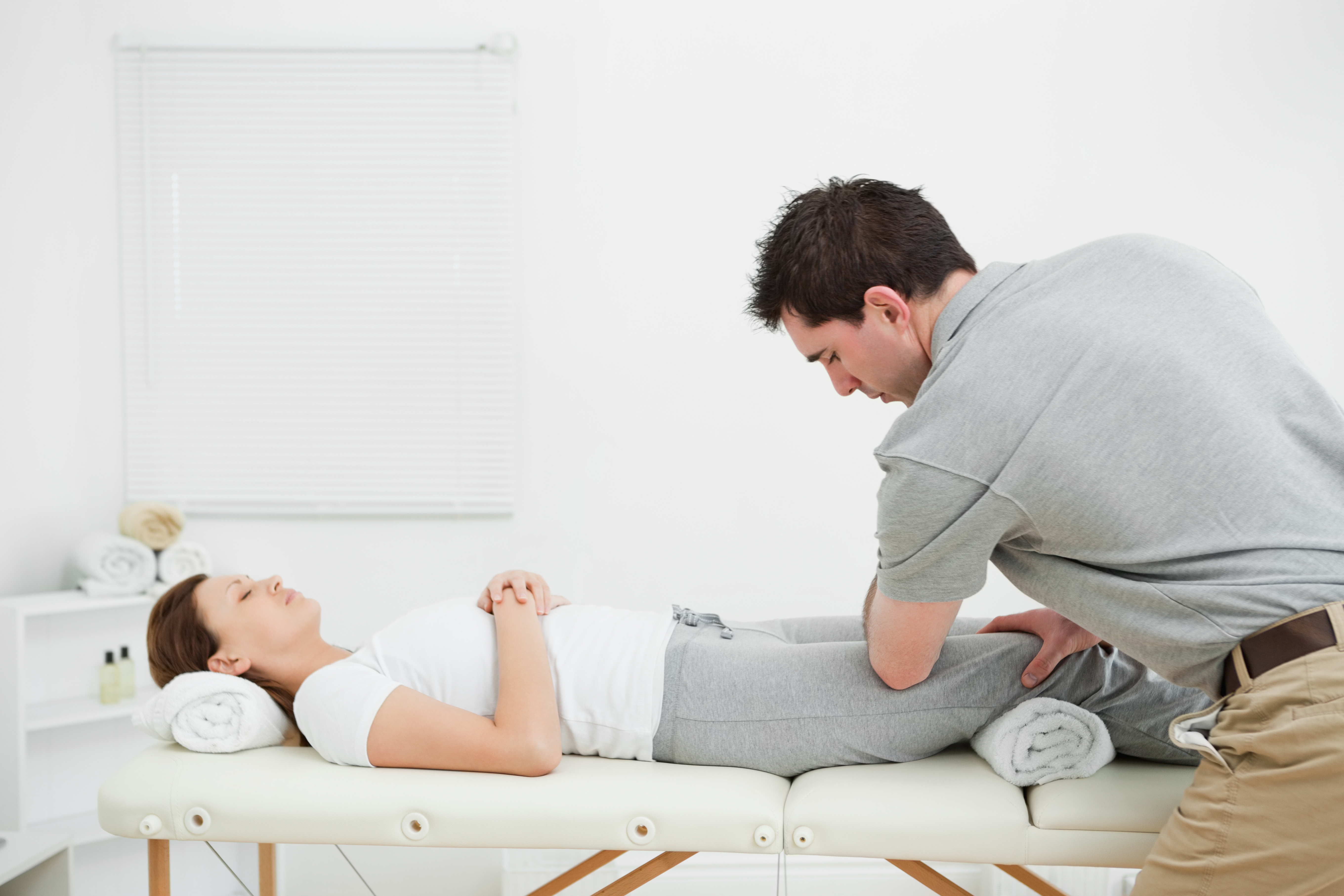 Woman lying on her back while being massaged by a man in a room